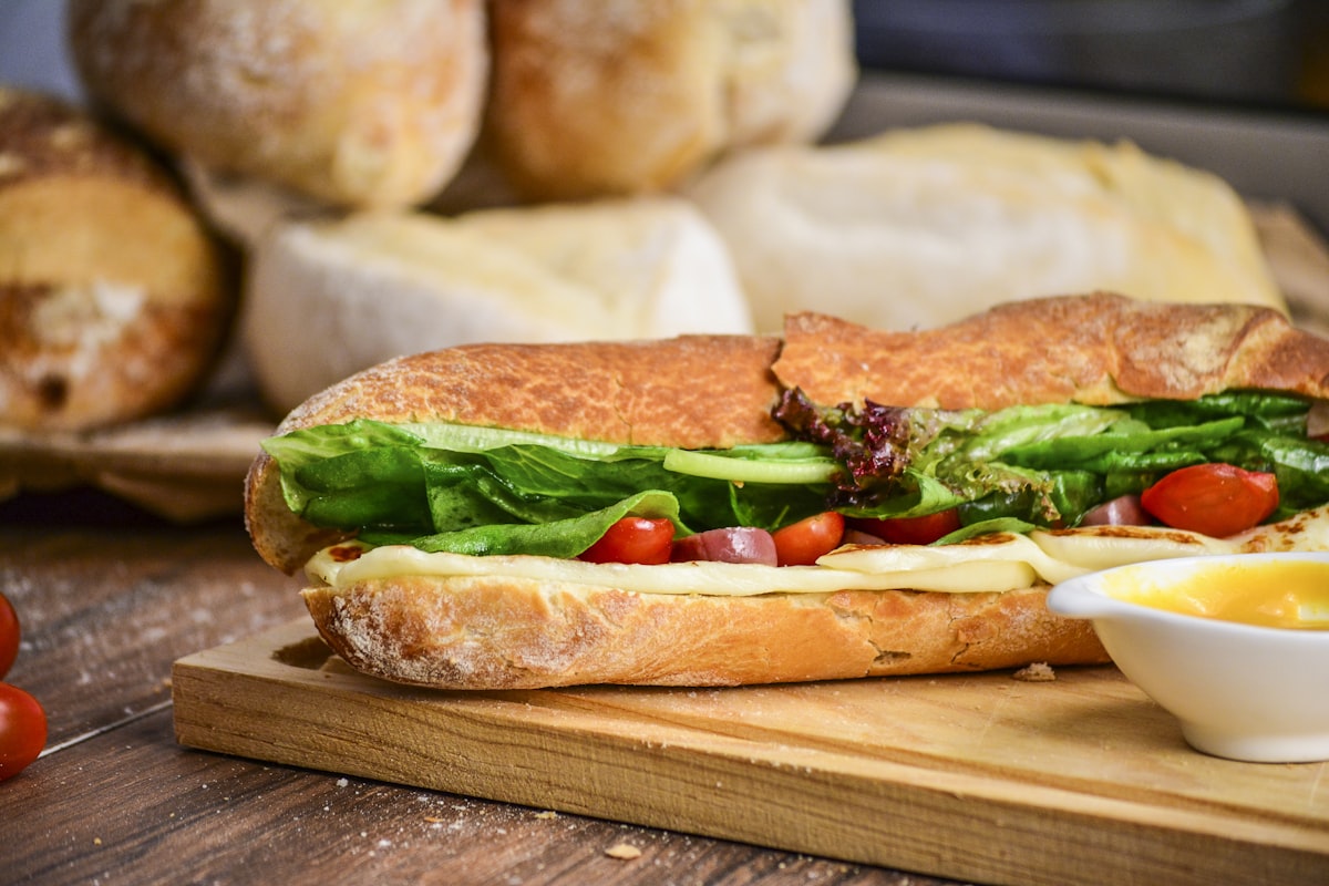 Fresh deli sub with cheese, lettuce, and tomato on a cutting board