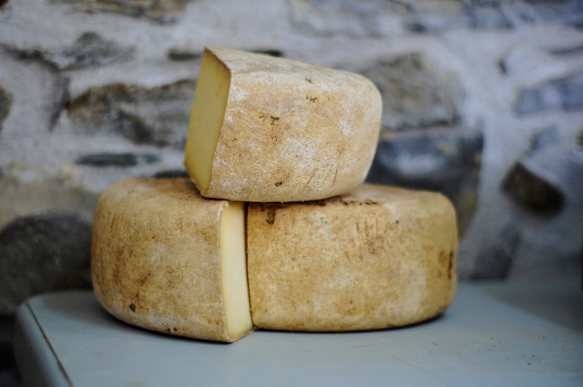 Rustic cheese wheels stacked with a wedge cut open