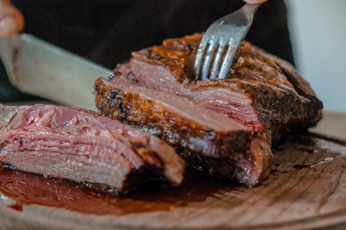 Roast beef being carved into thick slices on a wooden board